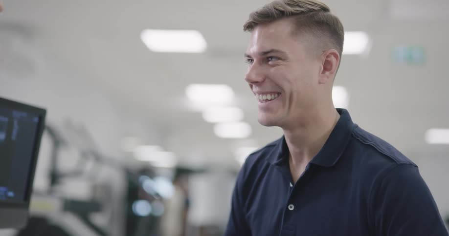 A man smiles and laughs while looking at something on a monitor
