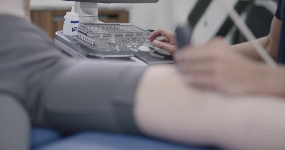 Man doctor examining patient knee at the clinic