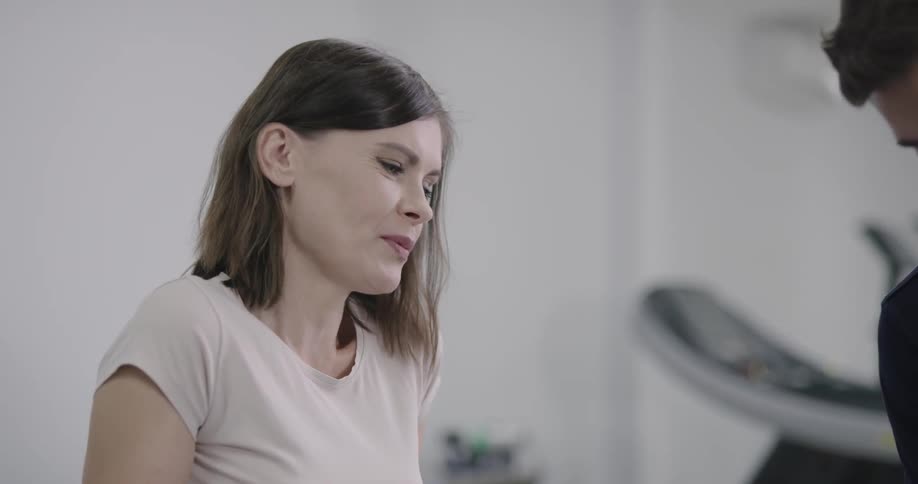 A man and a woman have a discuss while a man massages a womans leg in a medical facility