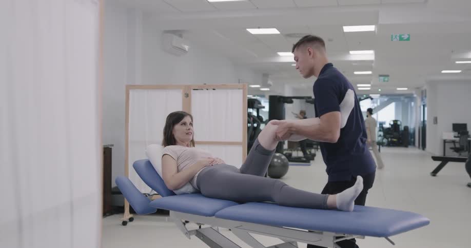 A physical therapist stretches a females leg on a table
