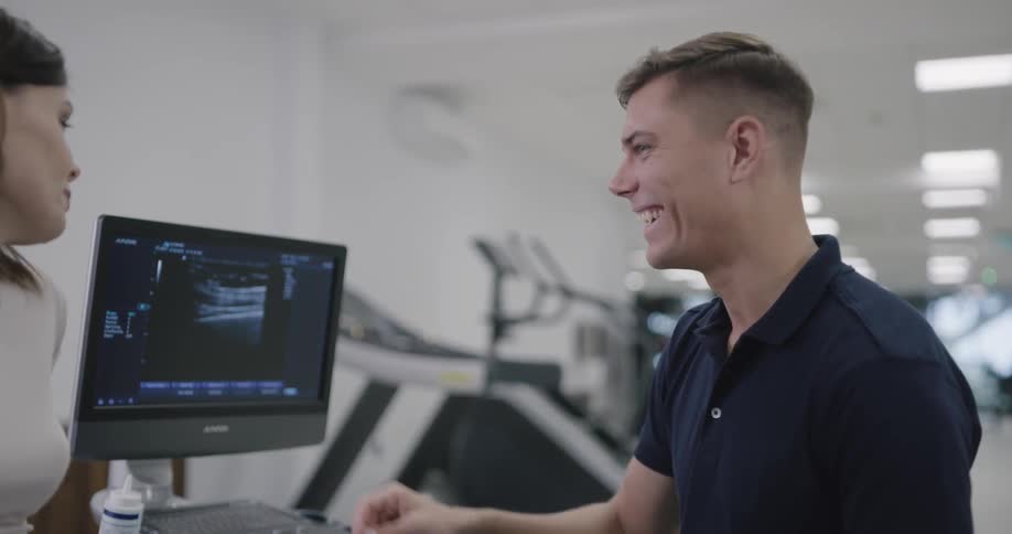 A man looks at a computer screen and talks to a woman about it