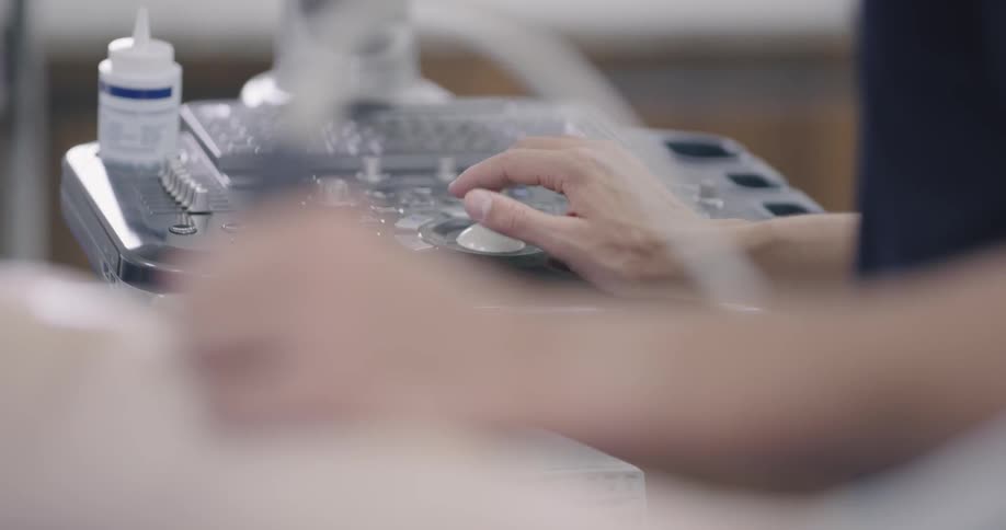 A person in dark blue scrubs operating an ultrasound machine