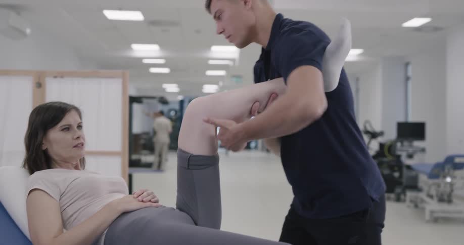 Man help to train woman leg at the gym