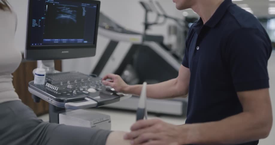 A patient is having her knee checked in the gym