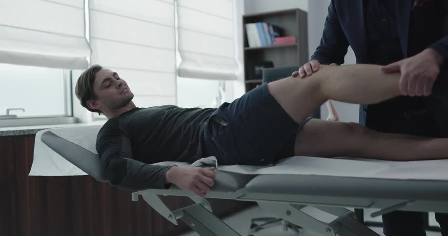 Man examines the leg of patient laying on examining table