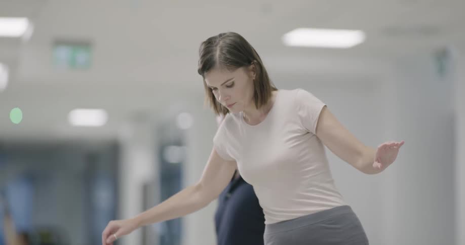 Woman steps upward and balances under trainer supervision