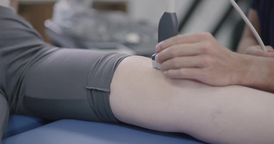 Technician examines knee with ultrasound wand
