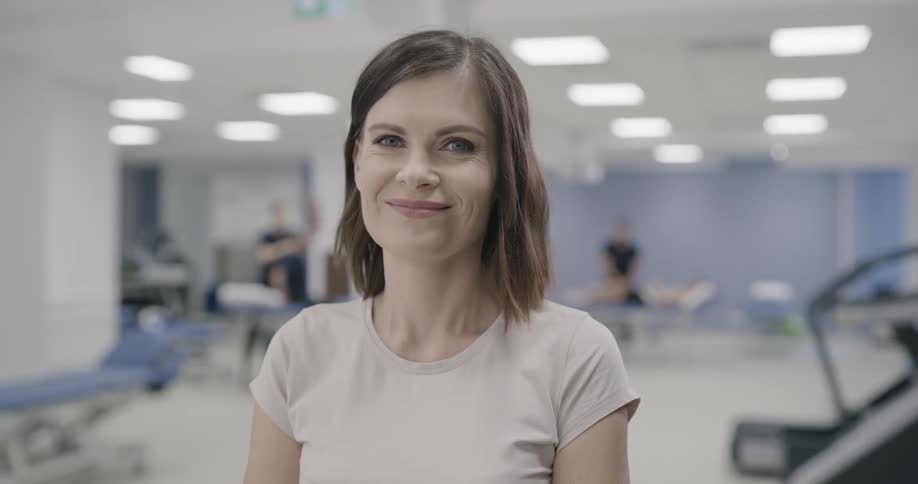 A woman is standing in a clinic and smiles
