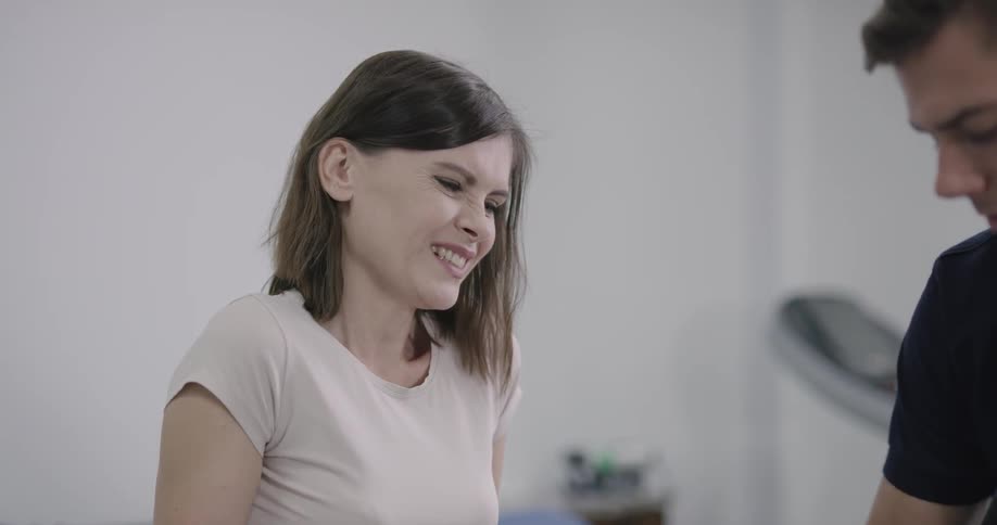 A woman stares painfully at a man who is caring for an injury she has on her leg
