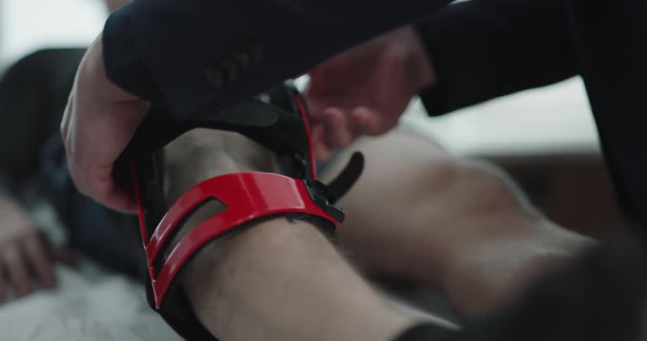 A doctor removes the leg brace of a male sitting on a table
