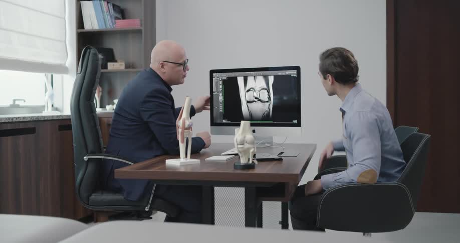 Physician describing a medical procedure on a monitor to a male patient