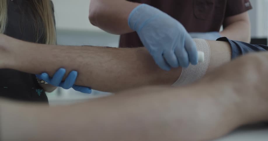 Doctor applying bandage to patient lying on stretcher