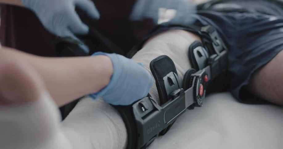 A doctor and nurse wrap a patients knee and apply a brace