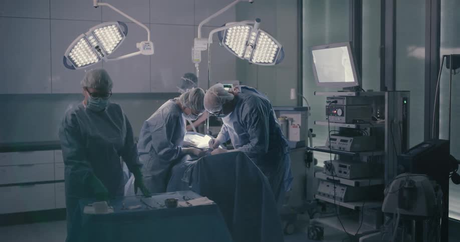 Doctors and nurses stand over an operating table and work on a patient