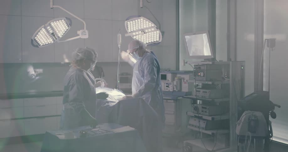 Two surgeons and a nurse are operating on someone in an operating room