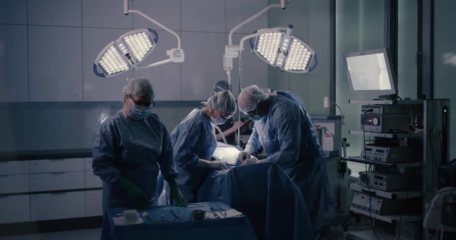Surgeons and nurses work on a patient in a surgical room