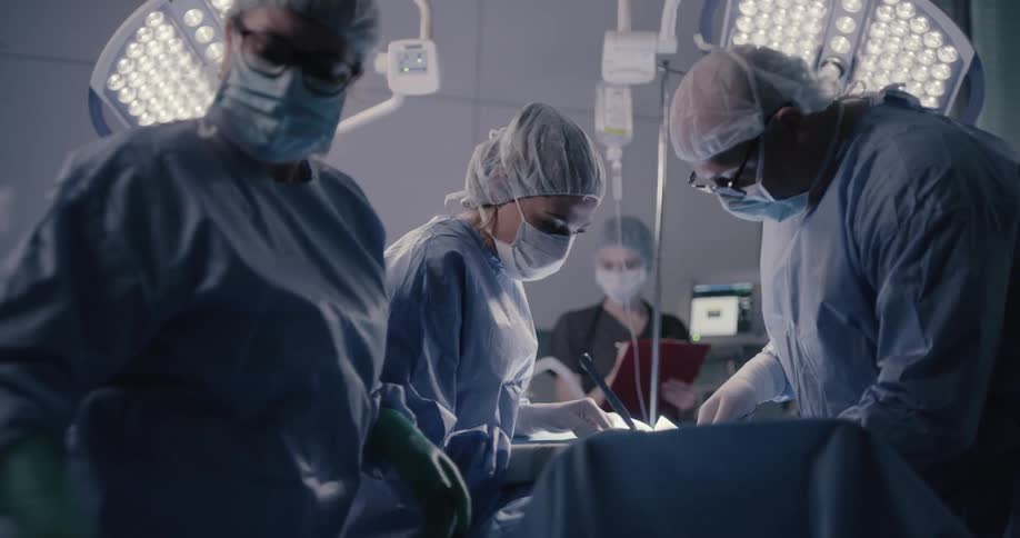A surgeon and nurses work on a patient in an operating room