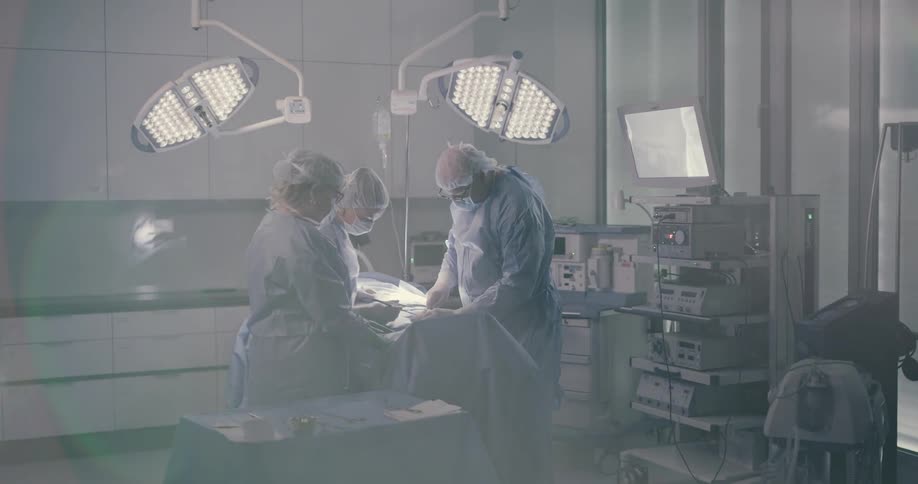 Three members of a surgical team operate in operating room