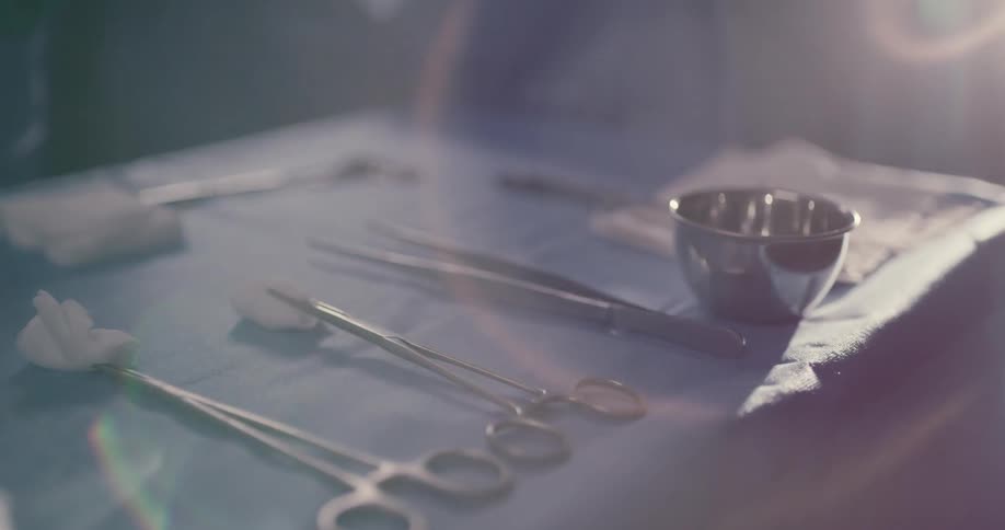 A doctor picks up surgical scissors from a table and sets it back down