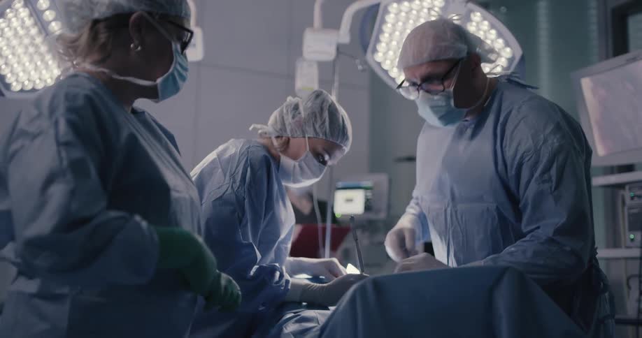 A doctor and nurses stand at an operating table and work on a patient