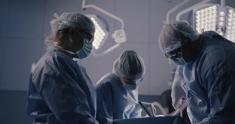 Doctors in face masks and scrubs perform surgery in an operating room