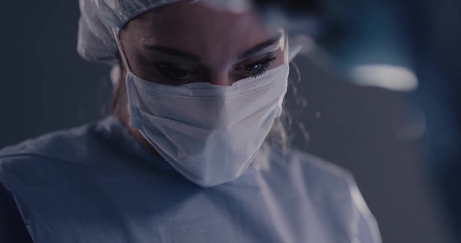 A woman in scrubs looks up from her patient