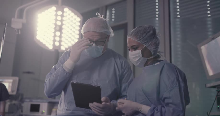 Doctor and nurse confer over tablet in operating room