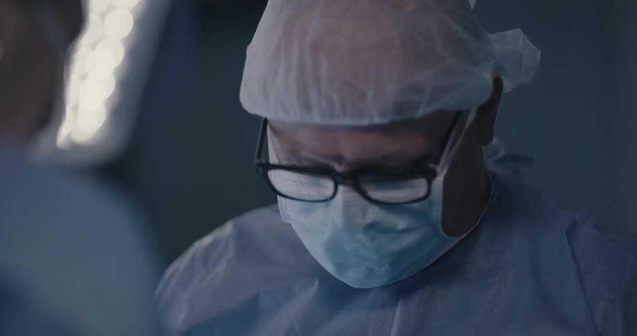 A doctor talks through his mask in an operating room
