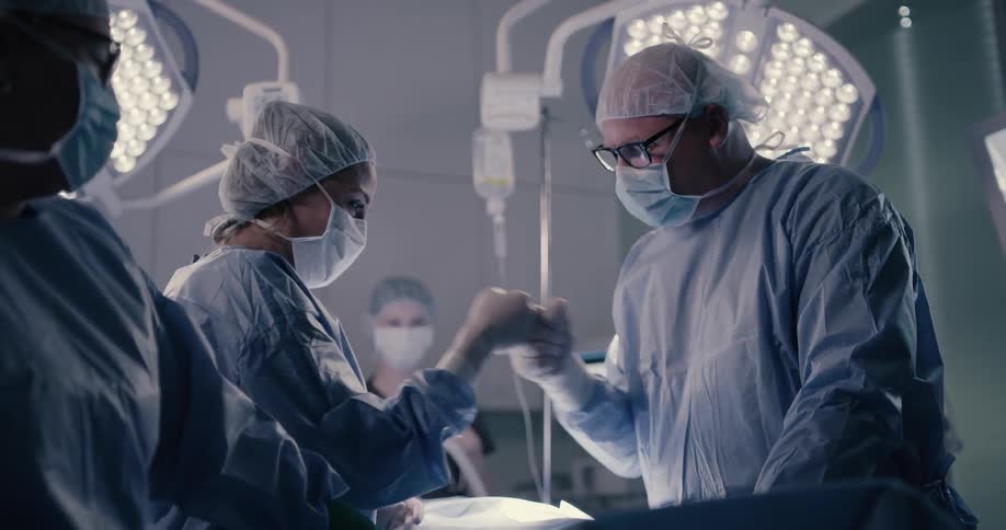 Medical personnel give a fist bump and special hand shake while in the surgical room