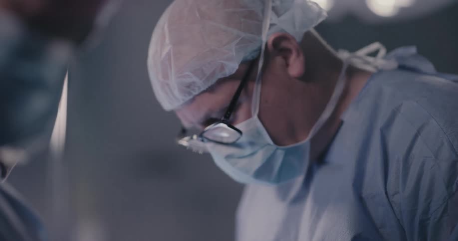 Light shines next to doctor operating in surgical theater