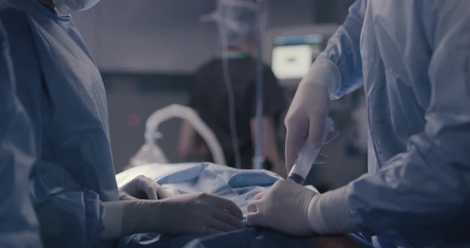 A surgeon rapidly pumping a syringe in and out of a person in an operating room