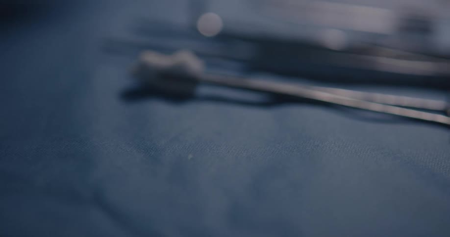 Surgery tools are arranged on a tray by a gloved hand