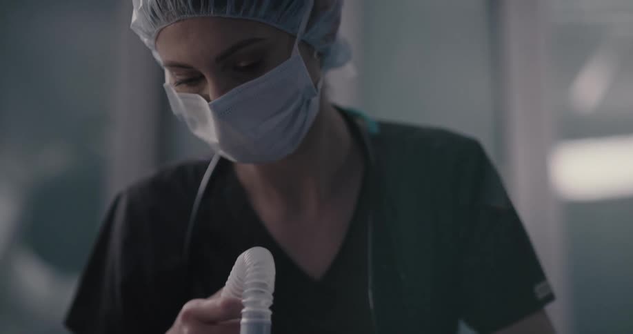A male is laying on his back when a female medical professional approaches and places an anesthesia supply mask over his mouth and nose