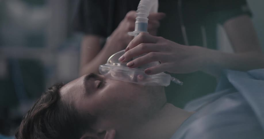 A nurse holds an oxygen mask to a male patient