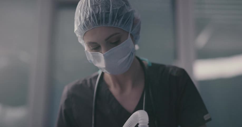 Nurse wearing mask removes medical breathing mask