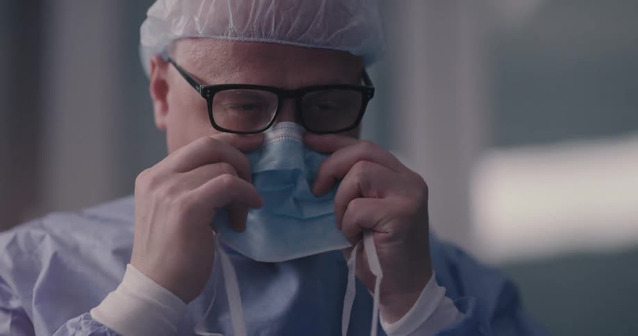 Medical personnel puts on head covering and medical mask