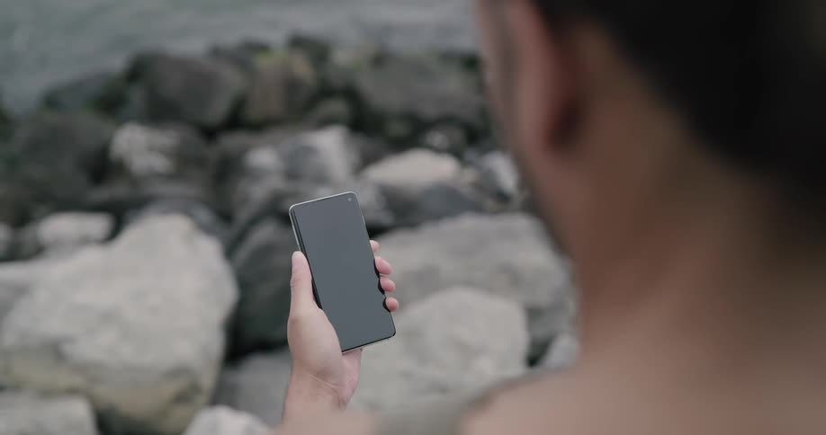 Someone looks at their phone on the beach