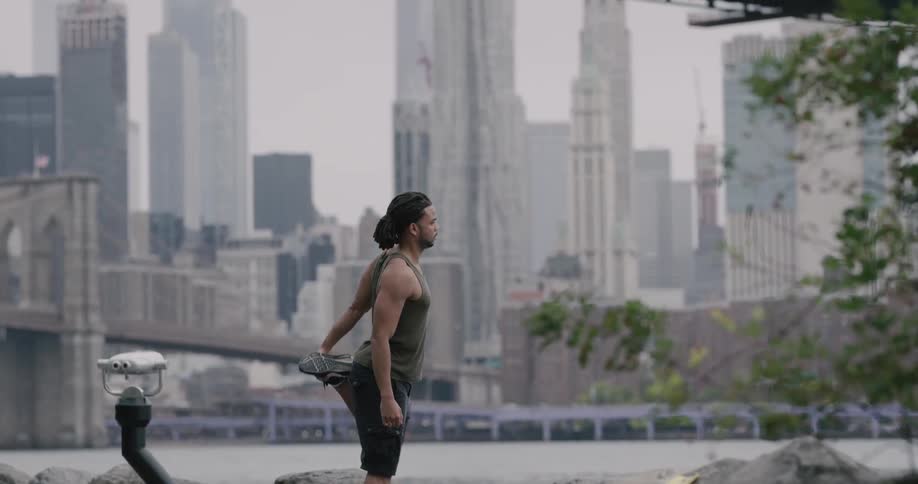 A man running stops to stretch his arms and legs
