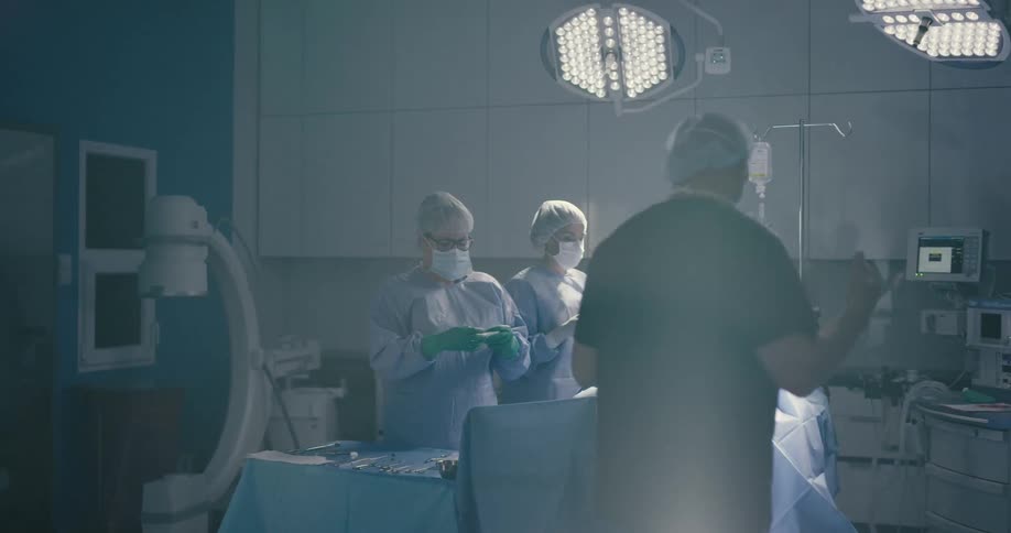 A doctor walks in to an operating room with a patient on the table