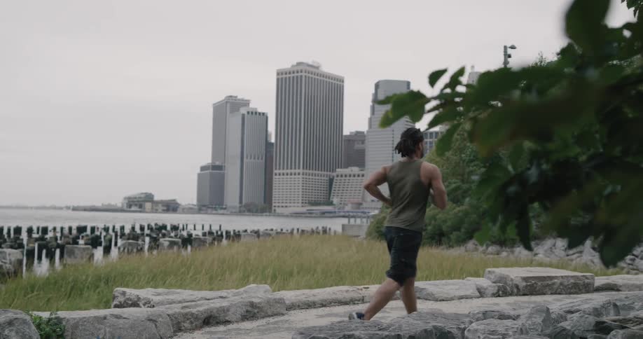 Black man runs along on the promenade in the city on a cloudy day