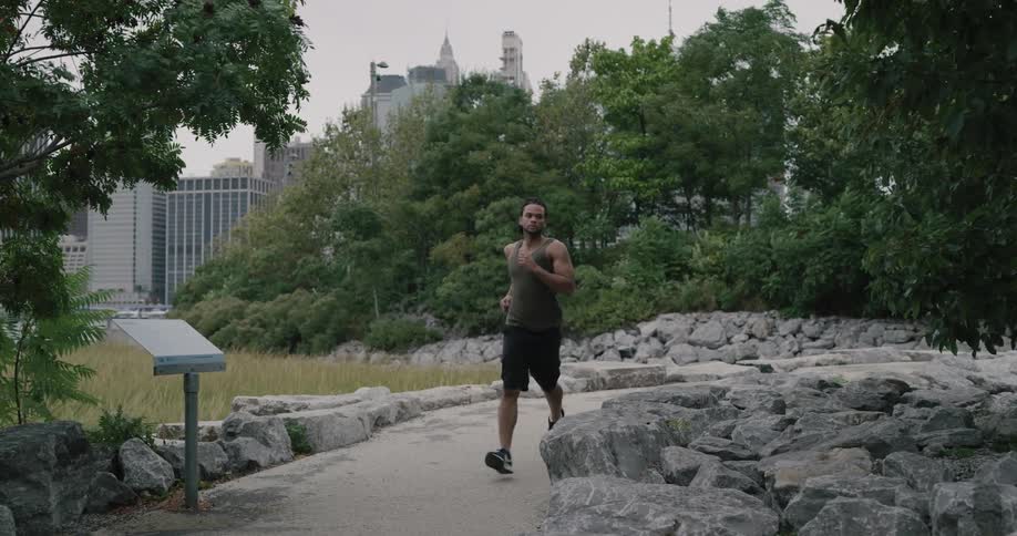 A young black jogging through a city park during the day