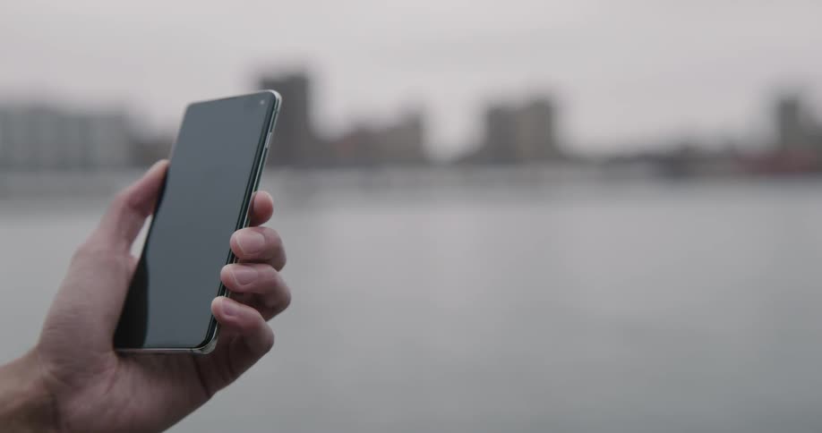 A person is using their cell phone by the water