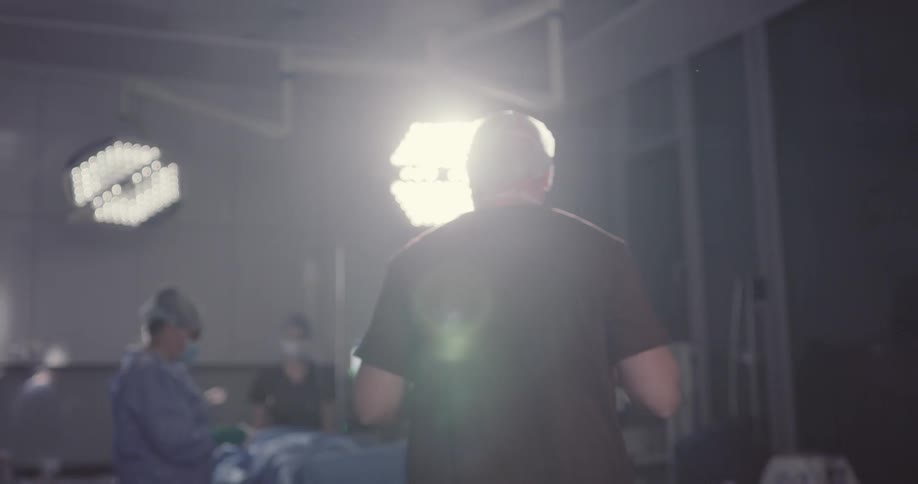 A male surgeon entering an operating room through double doors