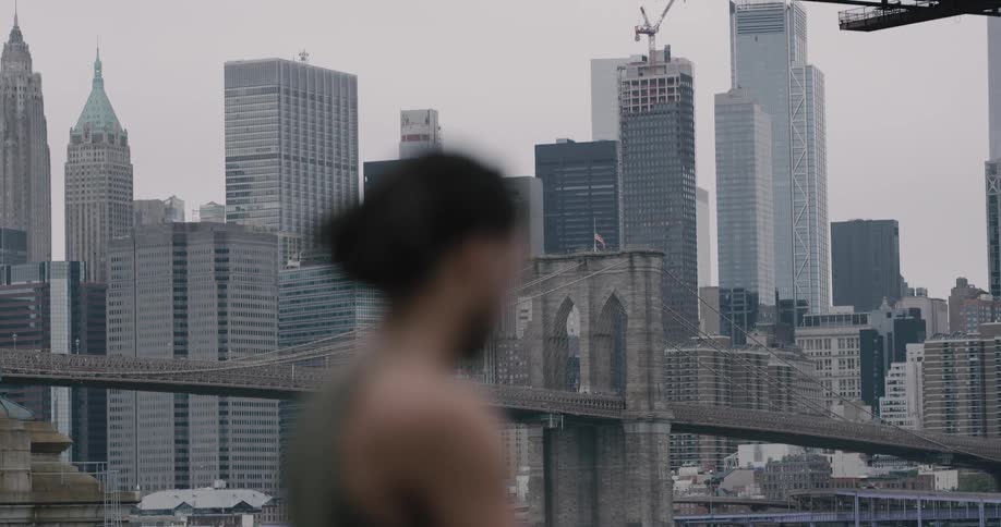 A male stops to take a break looking at his phone with the city in the background