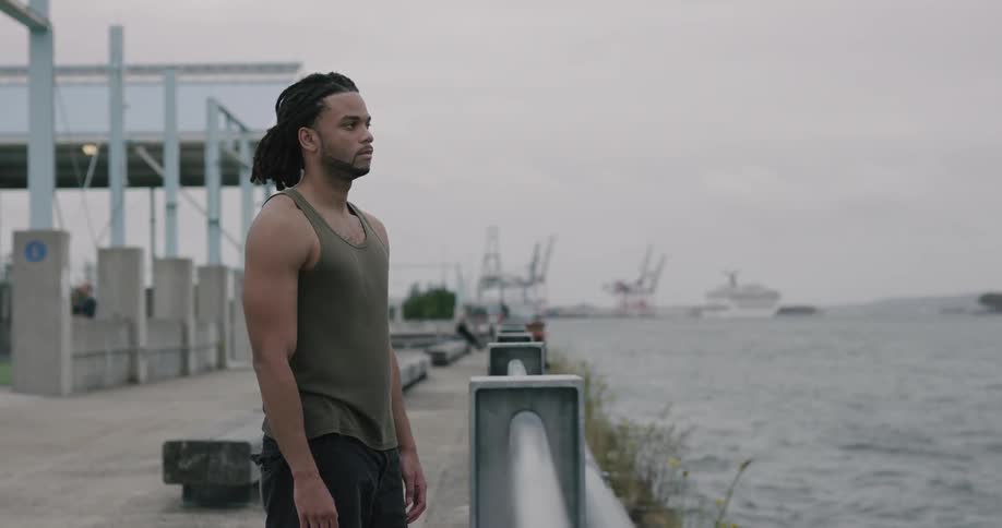 A man stains on the pier and looks out to the ocean water