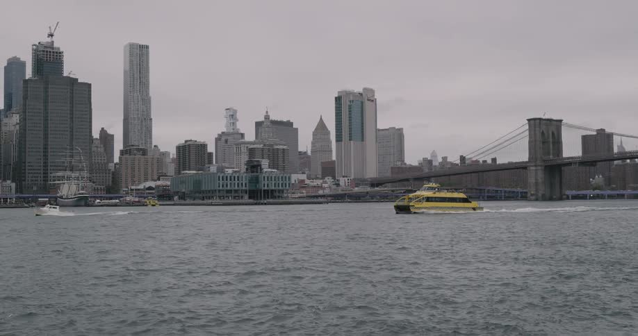 A yellow boat sailing through the river with city skyline background