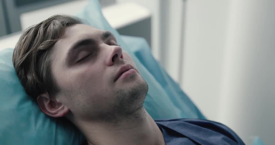 An unconscious man sleep on the bed after a surgery