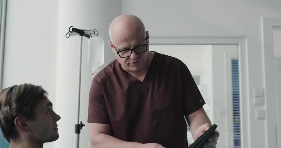 Doctor explaining to male patient medical procedure on a tablet