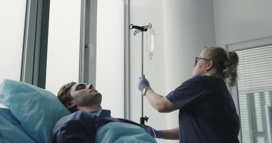 Nurse adjusts iv for bedridden unconscious patient