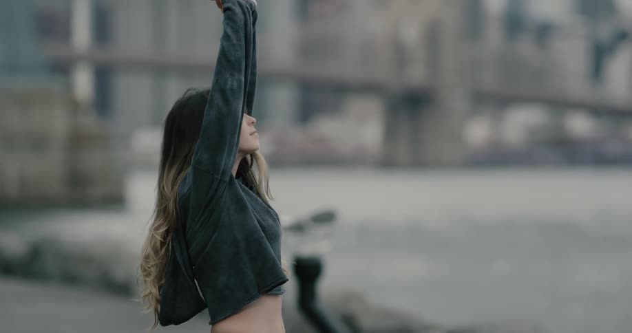 A woman stretches on the shore of a body of water